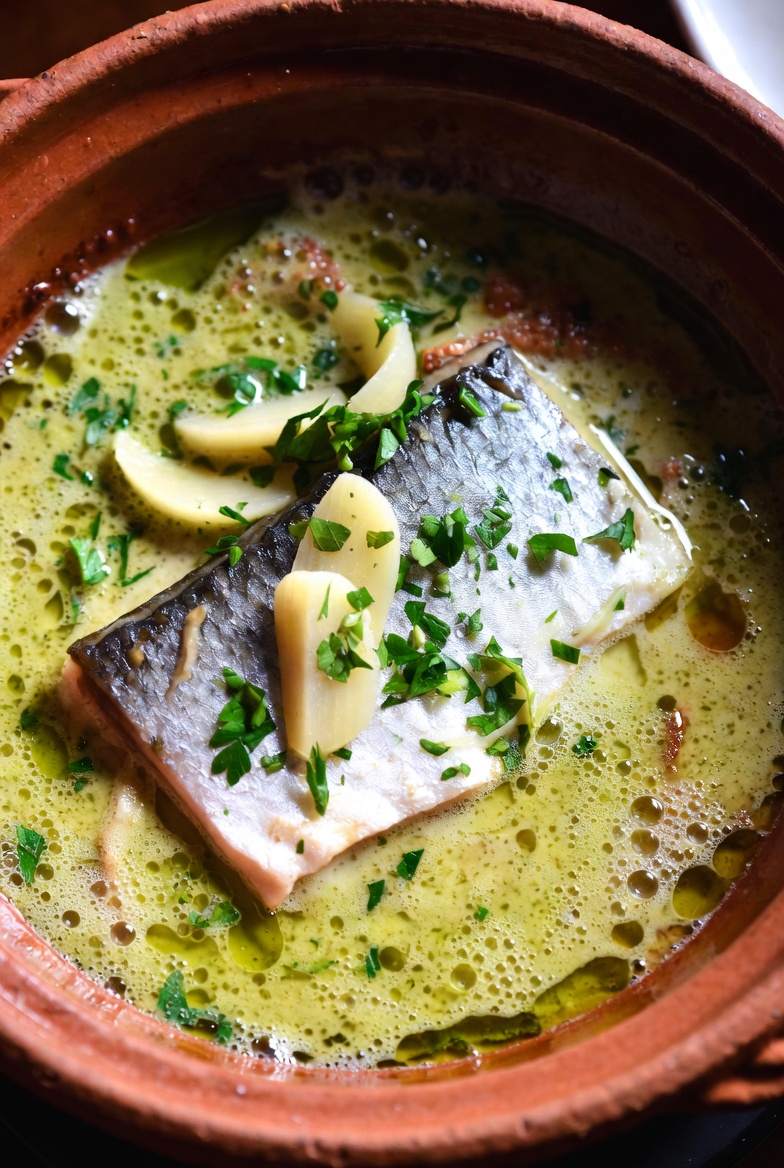 Kokotxas en salsa verde al pil-pil cociendo en cazuela de barro, mostrando la emulsi&oacute;n perfecta