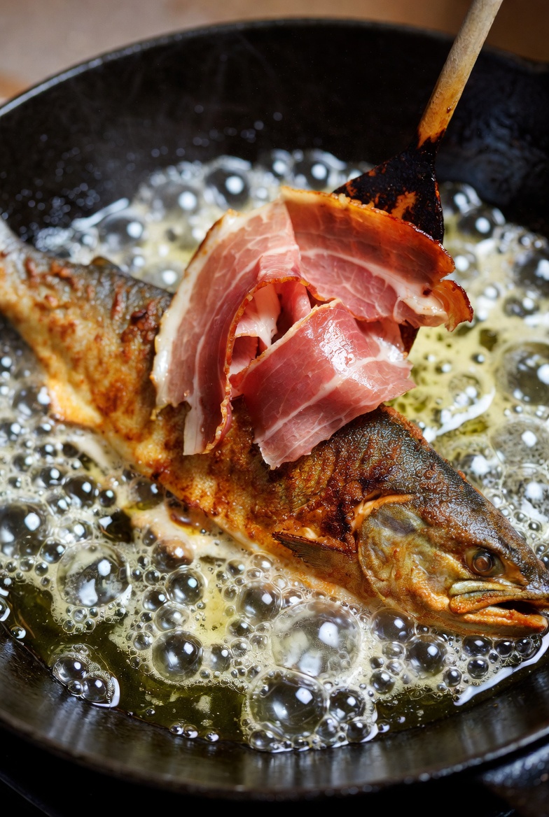 Trucha a la navarra fri&eacute;ndose en aceite de oliva, con jam&oacute;n serrano encima