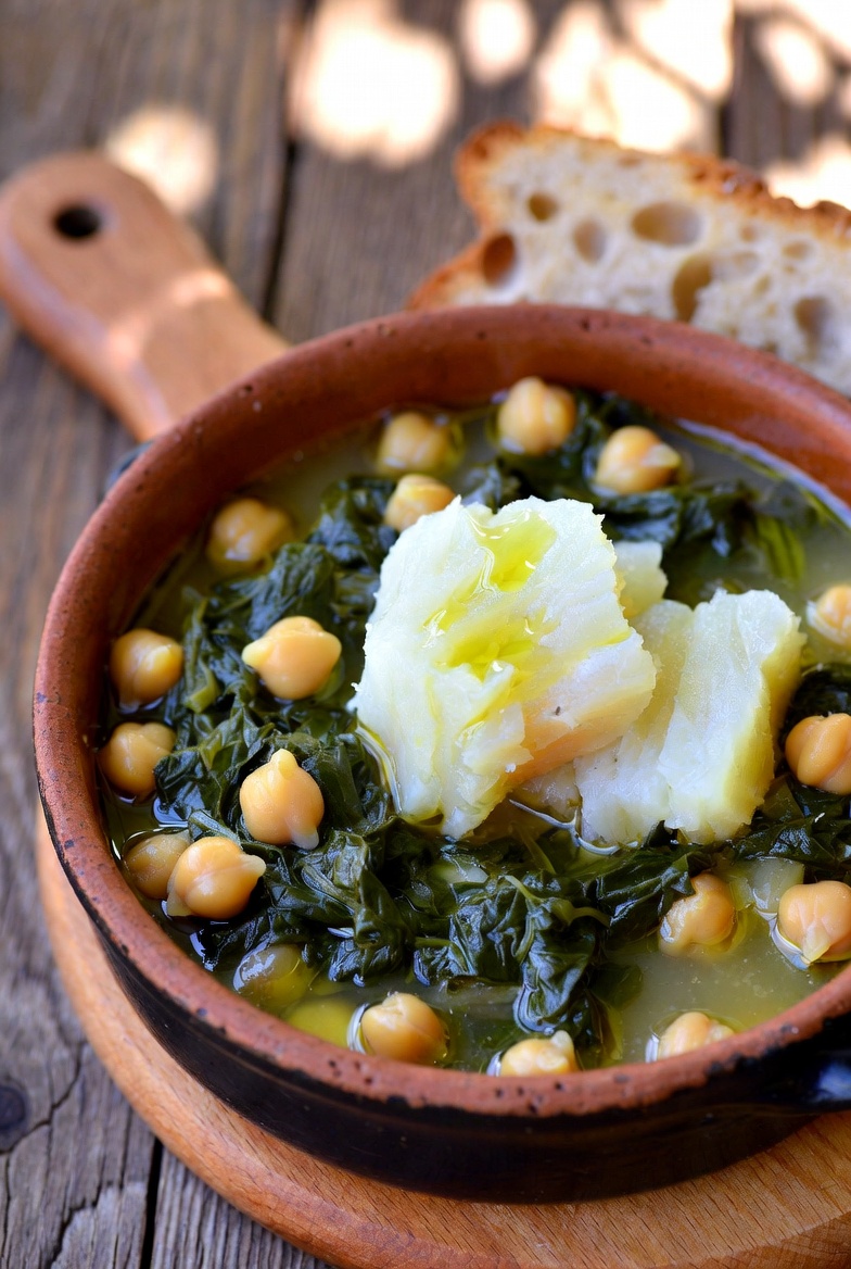 Guiso tradicional de garbanzos con espinacas y bacalao servido en cazuela de barro