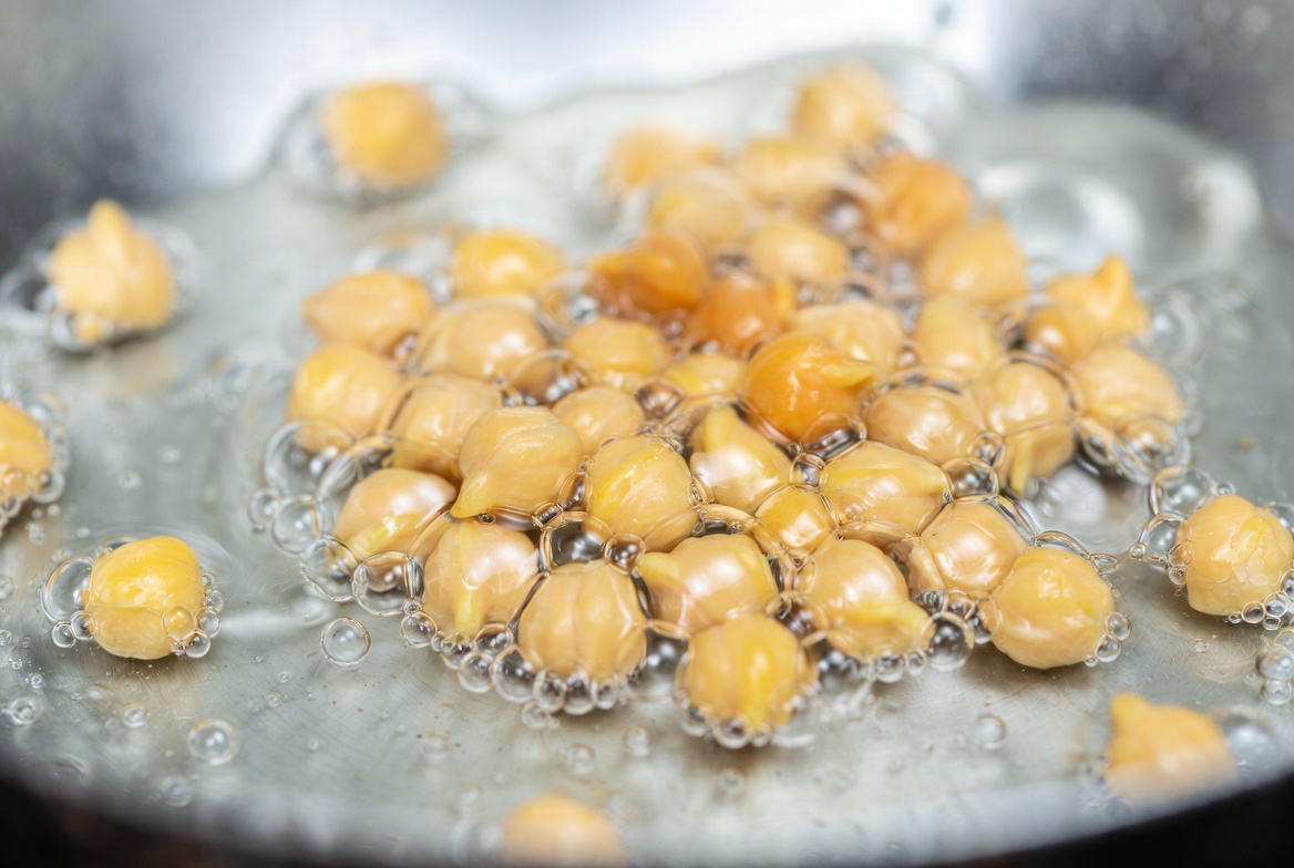 Garbanzos dor&aacute;ndose y crujiendo en aceite caliente para hacer garbanzos fritos.