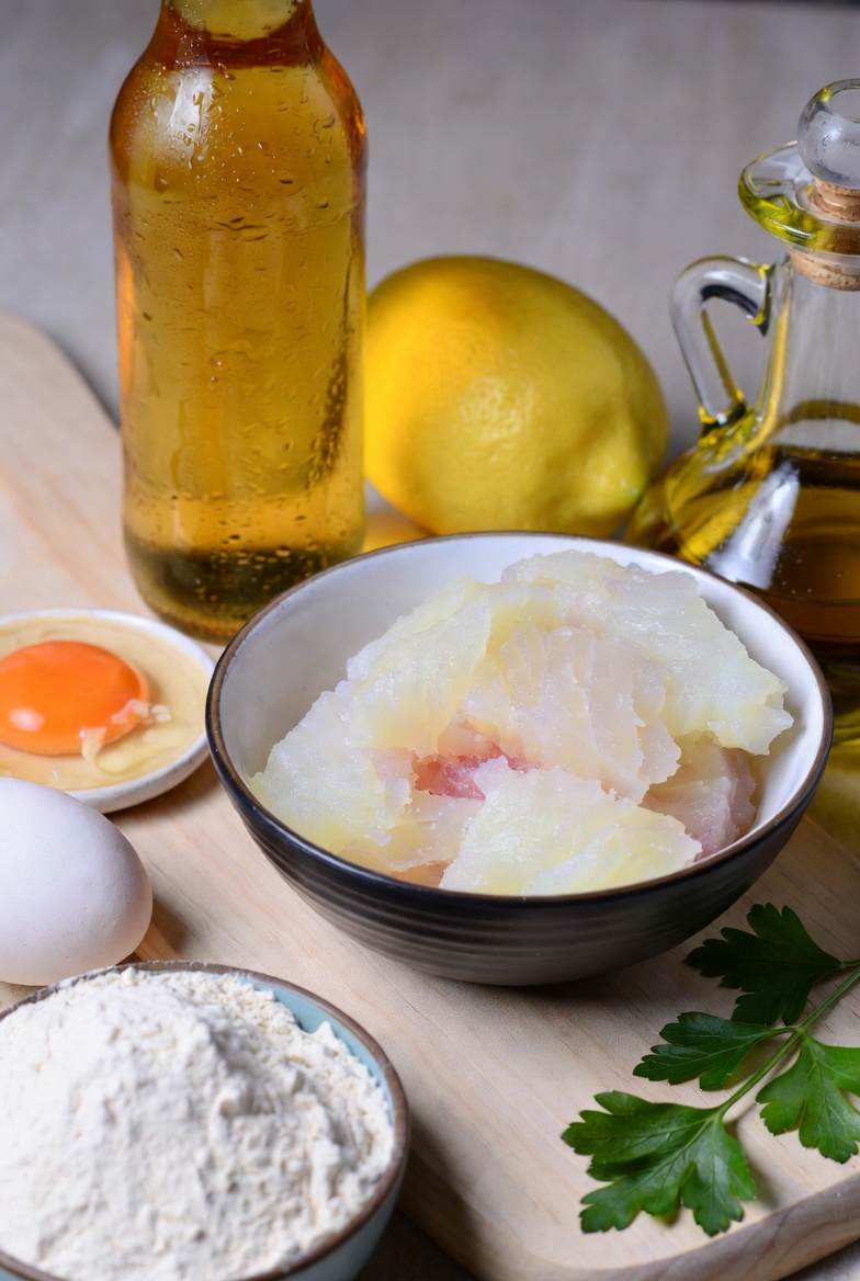 Ingredientes frescos para preparar Soldaditos de Pav&iacute;a caseros: bacalao, harina, cerveza, huevo, lim&oacute;n.