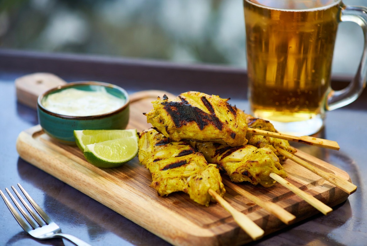 Pinchitos de pollo al curry terminados y listos para servir, con salsa y lima.