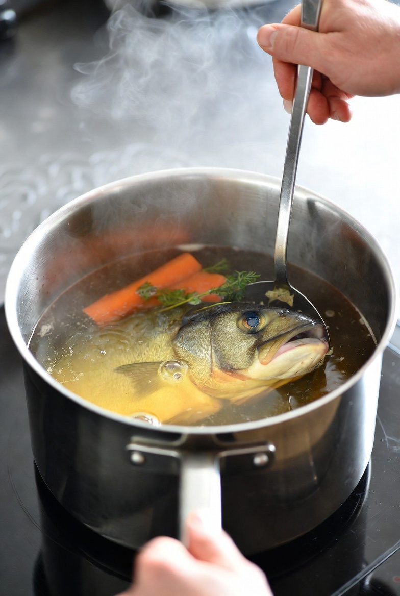 Caldo de pescado transparente cociendo a fuego lento en una olla, mostrando la t&eacute;cnica correcta.