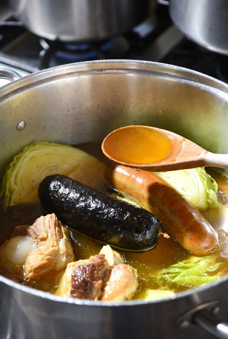Proceso final de desengrasar el caldo de la escudella i carn d'olla antes de servir