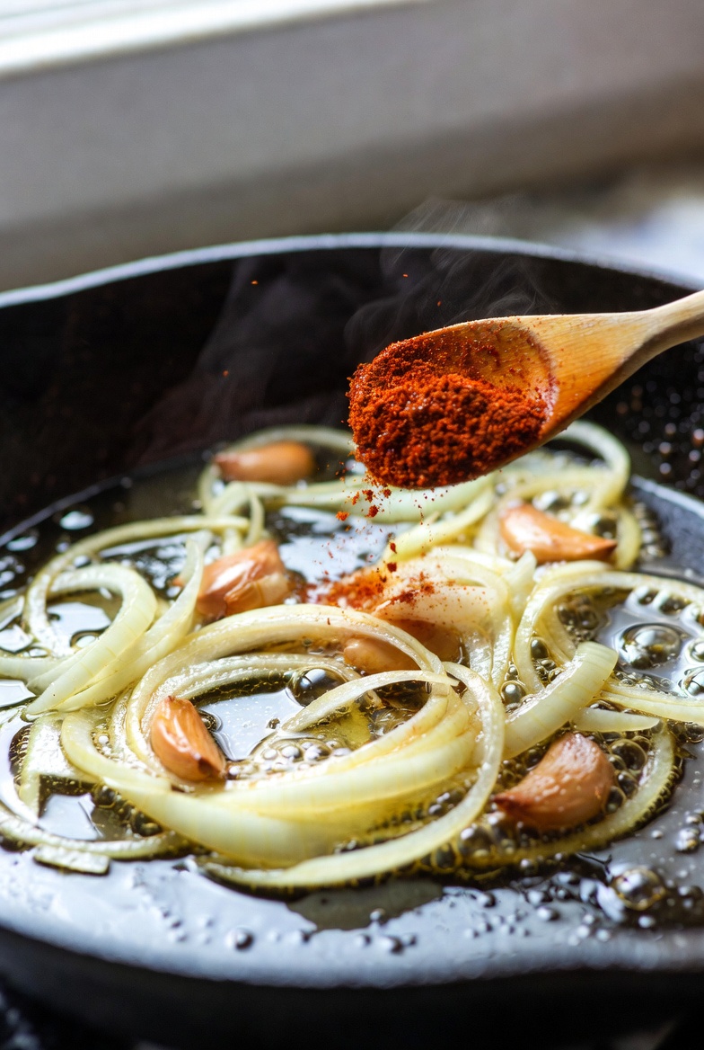 Momento clave de a&ntilde;adir piment&oacute;n al sofrito para garbanzos con espinacas y bacalao