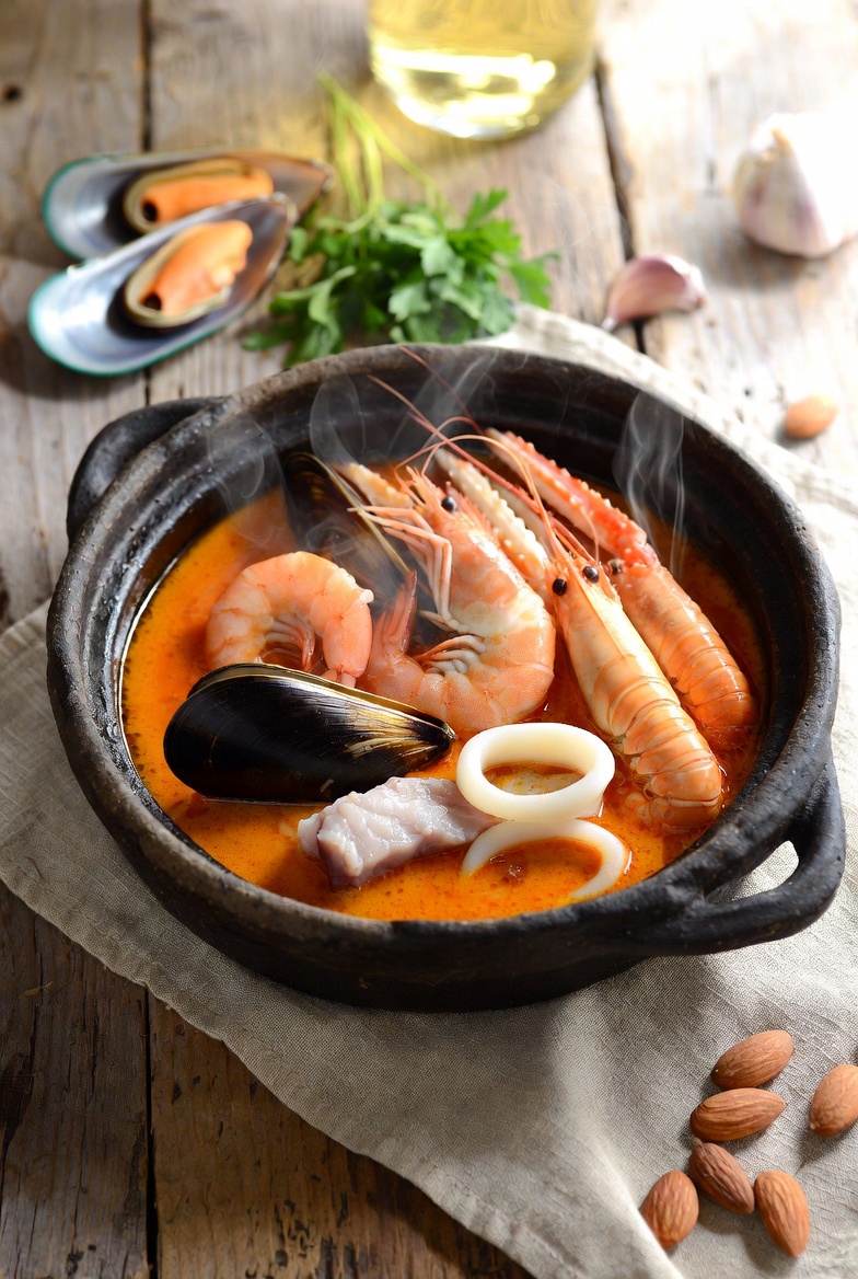 zarzuela de marisco servida en cazuela de barro, con gambas, mejillones, calamares y salsa espesa.