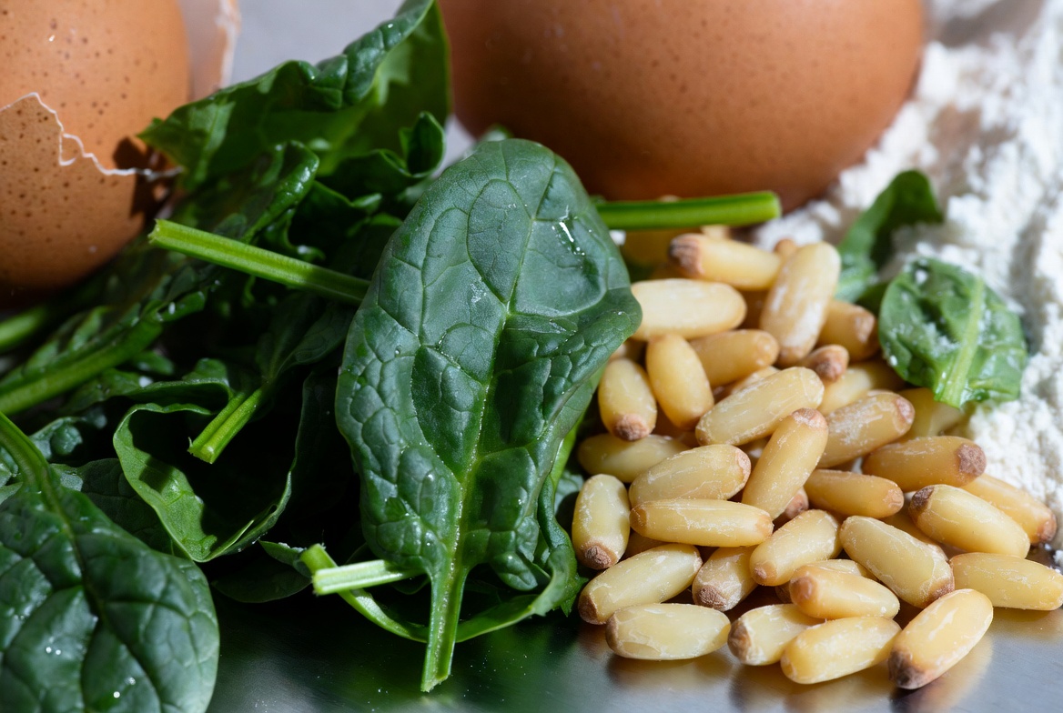 Ingredientes frescos para croquetas de espinacas y pi&ntilde;ones: espinacas, pi&ntilde;ones, huevo y pan