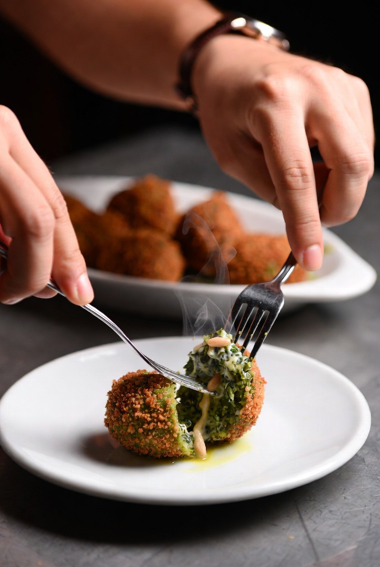 Momento de partir una croqueta de espinacas y pi&ntilde;ones reci&eacute;n hecha con un tenedor