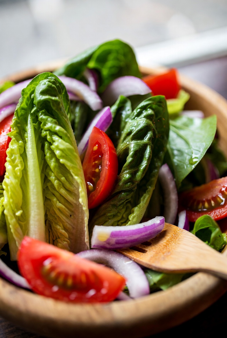 Ensalada de lechuga, tomate y cebolla servida en cuenco de madera