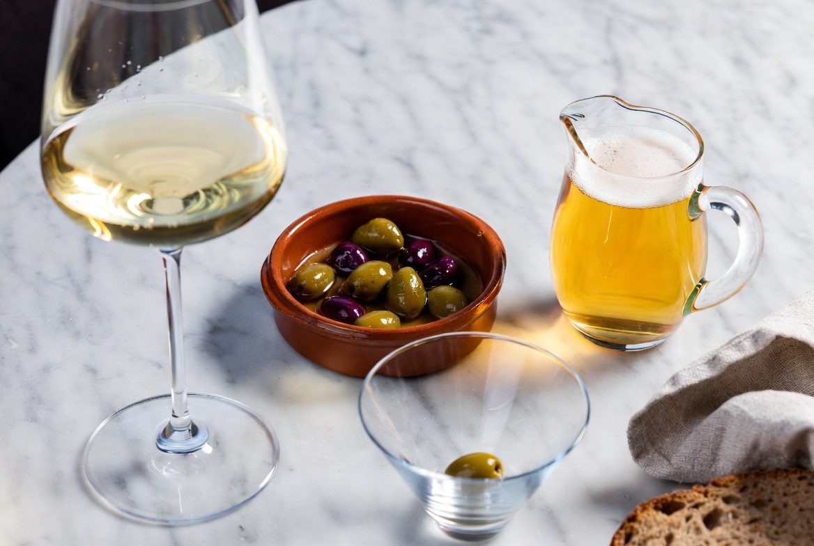 Maridaje perfecto de aceitunas ali&ntilde;adas con fino, cerveza y martini en un bar, estilo vida moderna.