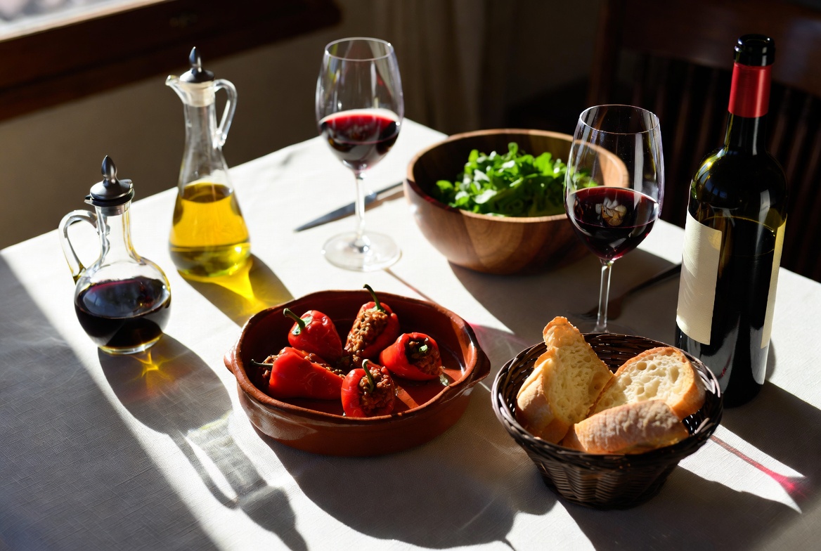 Mesa con pimientos del piquillo rellenos, vino tinto, ensalada y pan para compartir