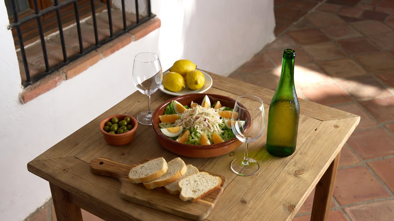 Mesa puesta con Remoj&oacute;n Andaluz, pan, vino blanco y aceitunas en un patio andaluz
